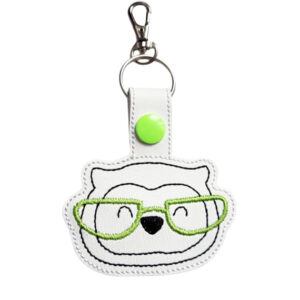 Smart Owl with Glasses Keyring featuring an embroidered owl face with lime green glasses on white faux leather, with a green snap button and silver clasp.