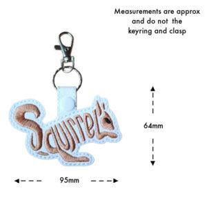 Embroidered squirrel word art keyring on white faux leather with brown stitching, measuring approximately 95mm wide and 64mm high, excluding the keyring and clasp.