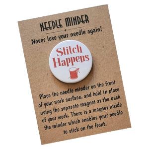 Round needle minder with white background and red text reading ‘Stitch Happens,’ with a spool-of-thread graphic below. Displayed on kraft card packaging that says ‘Needle Minder – Never lose your needle again!’ with usage instructions.