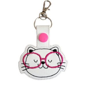 Sweet Kitten with Glasses Keyring featuring an embroidered kitten face wearing pink glasses on white faux leather, with a pink snap button, split ring, and swivel clasp.
