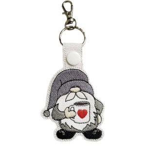 Coffee gnome keyring made from faux leather, featuring an embroidered gnome wearing a hat and holding a mug with a heart on it, attached to a silver keyring ring and lobster clasp.