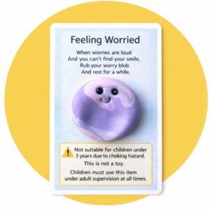 Handmade purple polymer clay Blob worry stone attached to a mindfulness backing card with poem and safety warning stating not suitable for children under 3 years due to choking hazard and not a toy, photographed on a yellow background