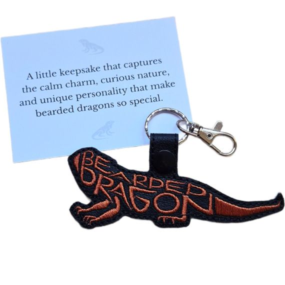 White keepsake card displayed with a black faux leather bearded dragon word art keyring with copper stitching.