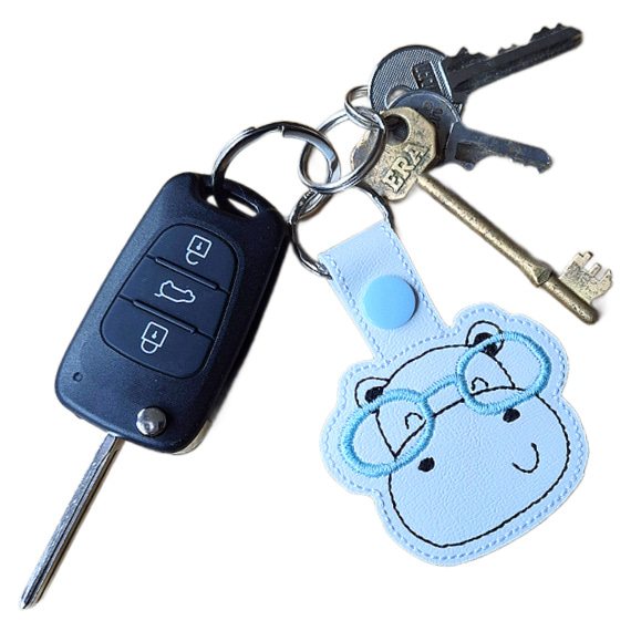 Hippo face keyring with blue glasses attached to a set of keys, showing the keyring in everyday use.