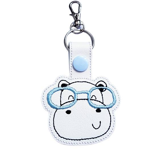 Hippo face keyring with blue glasses, made from white faux leather with a metal split ring and swivel clasp.