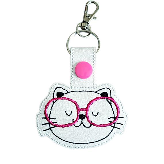 Kitten face keyring with pink glasses, made from white faux leather with a metal split ring and swivel clasp.