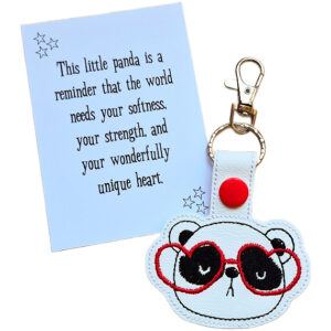 Panda face keyring made from white faux leather with embroidered facial details, black eye patches and bright red heart-shaped glasses, displayed beside a printed keepsake card with the message ‘This little panda is a reminder that the world needs your softness, your strength, and your wonderfully unique heart.’