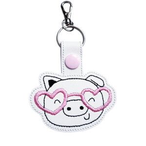 Pig face keyring with pink heart glasses, made from white faux leather with a metal split ring and swivel clasp.