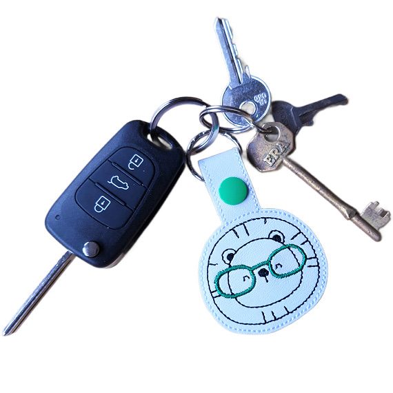 Lion face keyring with green glasses attached to a set of keys, showing the keyring in everyday use.