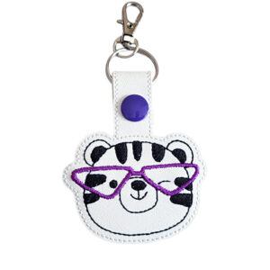 Tiger face keyring with purple glasses, made from white faux leather with a metal split ring and swivel clasp.