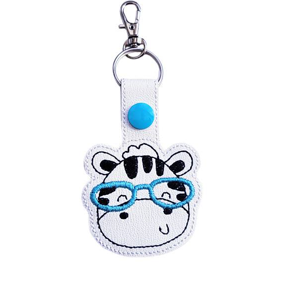 Zebra face keyring with teal glasses, made from white faux leather with a metal split ring and swivel clasp.
