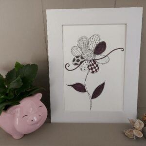 Framed floral illustration on a shelf with a small plant and decorative objects