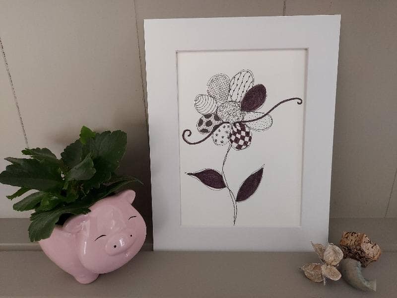 Framed floral illustration on a shelf with a small plant and decorative objects