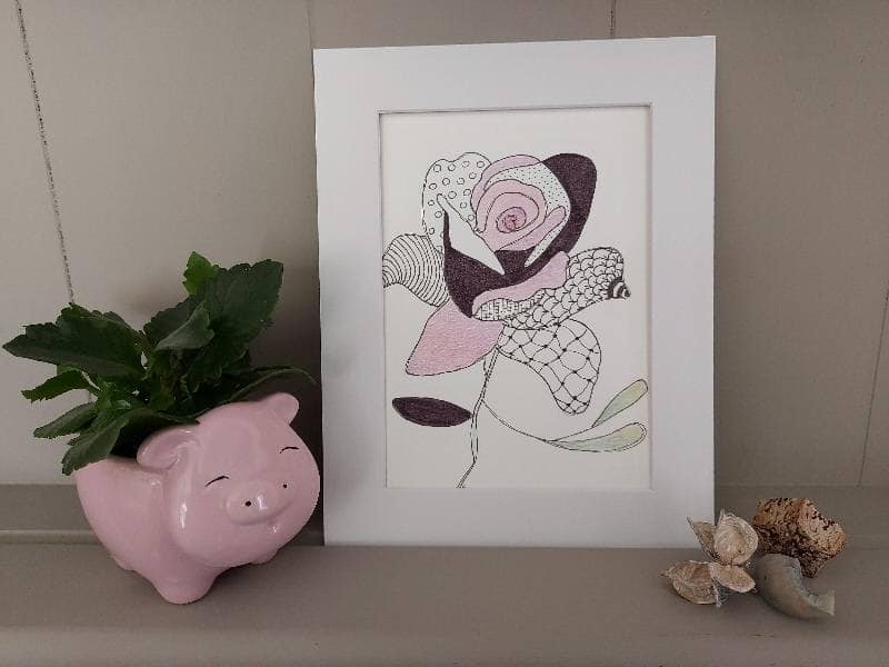 Framed floral illustration on a shelf with a small plant and decorative objects