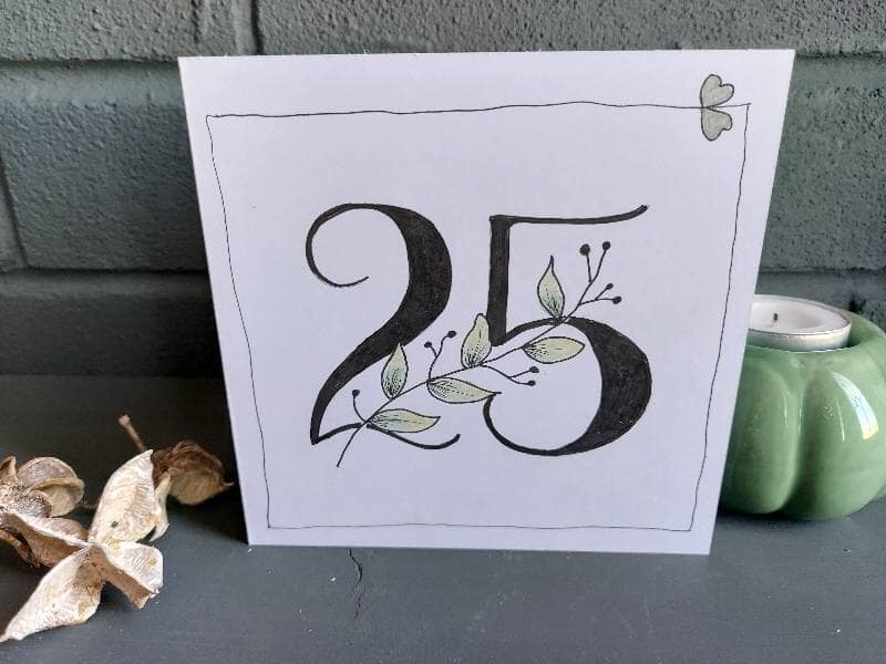 white 5"x5" card with bold 25 in centre and green leaf stem winding through, 2 silver hearts in top right corner