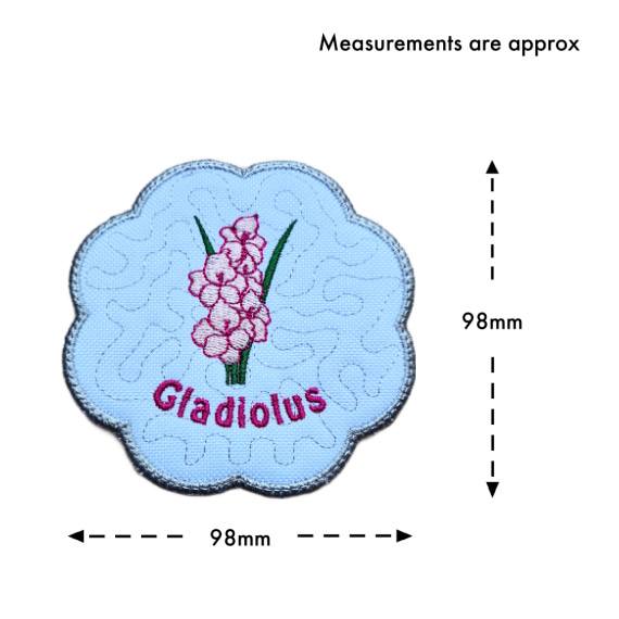 August birth flower candle coaster size guide showing the embroidered gladiolus design with stitched text and scalloped silver border, measuring approximately 98mm x 98mm.