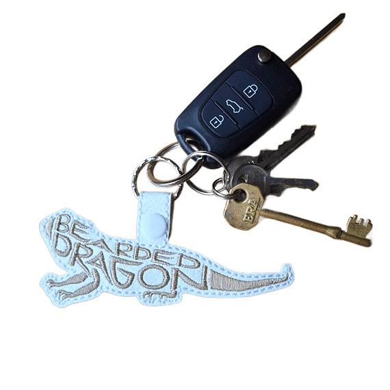 White faux leather bearded dragon word art keyring attached to a set of keys, showing its size and everyday use.