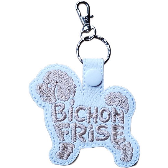 White faux leather Bichon Frise word art keyring, Design 1, with beige embroidered lettering, white snap fastener and silver clip.