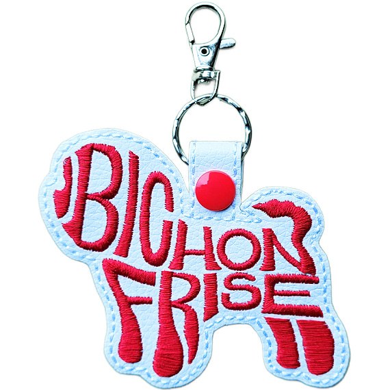 White faux leather Bichon Frise word art keyring, Design 2, with red embroidered lettering, red snap fastener and silver clip.
