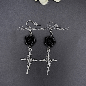 Picture shows a pair of drop earrings featuring a black rose bead and silver cross charms in a gothic style