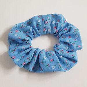 Handmade blue cotton scrunchie with tiny pink and white floral print on a white background