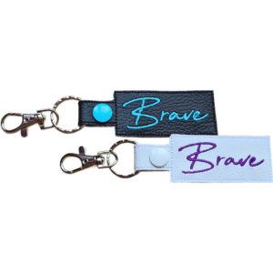 Two embroidered Brave keyrings in faux leather, with the word 'Brave', with sturdy metal keyring hardware.