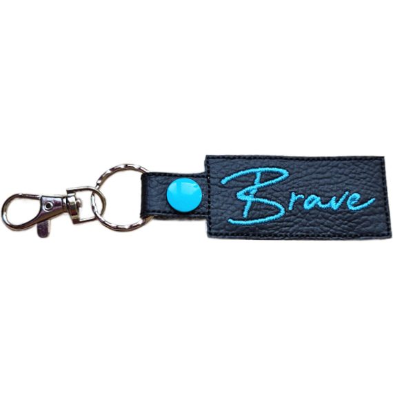 Embroidered Brave keyring in black faux leather, with the word 'Brave' stitched in turquoise and sturdy metal keyring hardware.