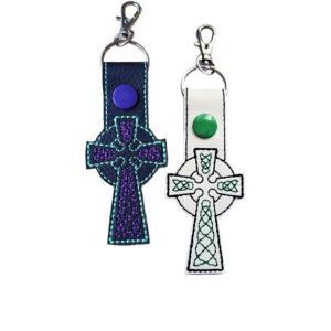 Black and white faux leather Celtic Cross keyrings with embroidered knotwork-style details, coloured snaps and silver metal clasps.