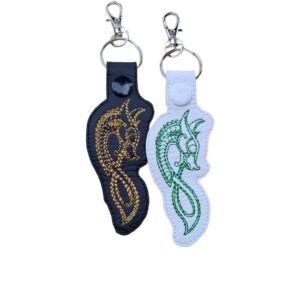 Black and white Celtic Dragon keyrings with embroidered dragon designs and silver metal lobster clasps.