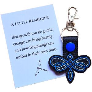 Black Celtic Dragonfly keyring with blue embroidered knotwork-style design, shown with a matching keepsake card about growth, change and new beginnings.