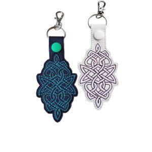 Black and white Celtic Knot keyrings with embroidered knotwork designs, coloured snaps and silver metal clasps.