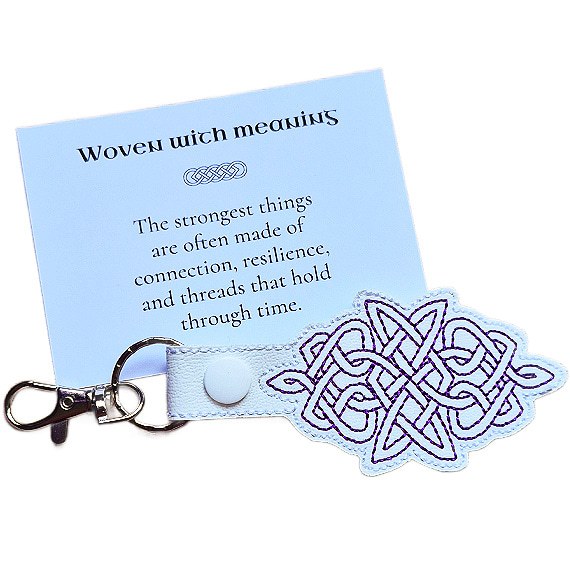 White Celtic Knot keyring with purple embroidered knotwork design, shown with a matching keepsake card about connection, resilience and meaning.