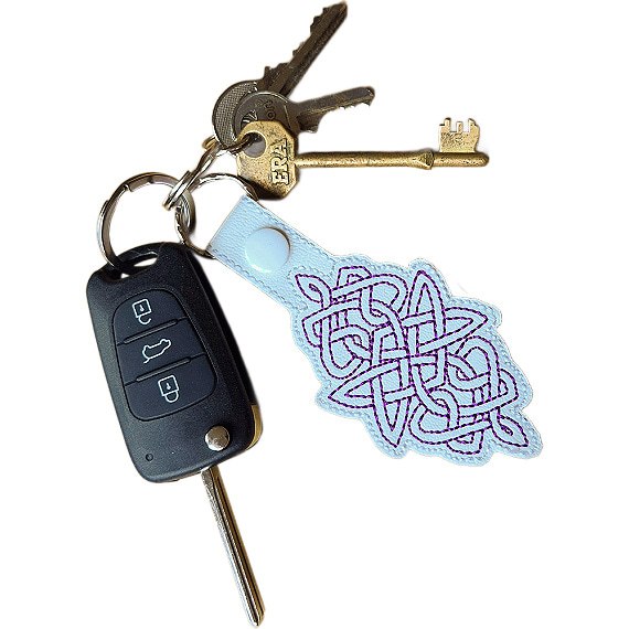 White Celtic Knot keyring attached to a set of keys, showing its size and everyday use.