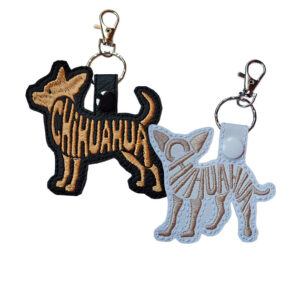 Two embroidered Chihuahua word art keyrings in black and white faux leather, with metal clips and matching snap fasteners.