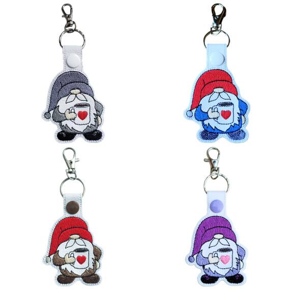 Embroidered coffee gnome keyrings shown in four colour options, each featuring a cute gnome holding a mug with a heart and sturdy metal hardware.