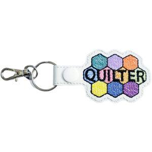 White faux leather quilter keyring embroidered with a colourful patchwork-style design and the word 'Quilter', finished with a metal clasp.