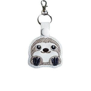 White faux leather cute sloth keyring with an embroidered kawaii sloth face, white snap fastening and silver lobster clasp hardware.
