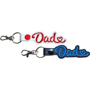 Dad Heart keyrings shown in white and black faux leather, with embroidered Dad lettering, heart detail and sturdy metal keyring hardware.