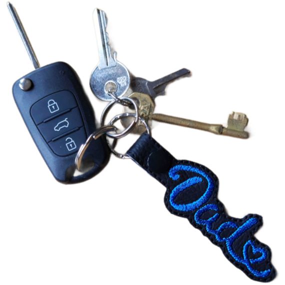 Black faux leather Dad Heart keyring with blue embroidered Dad lettering and heart detail, attached to a set of keys.