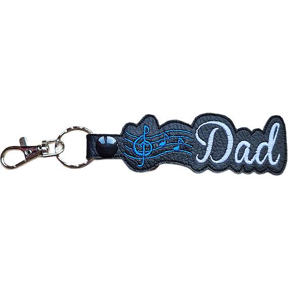 Black faux leather Dad Music Note keyring with blue embroidered musical notes, white Dad lettering and sturdy metal keyring hardware.