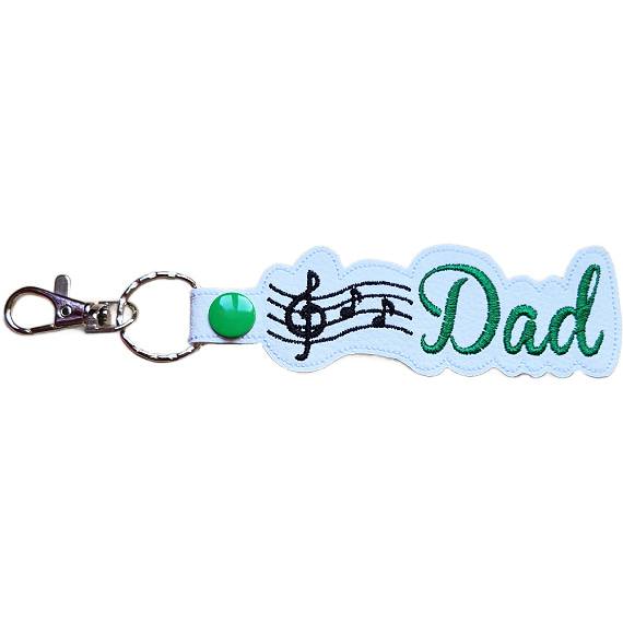 White faux leather Dad Music Note keyring with green Dad lettering, black musical notes and sturdy metal keyring hardware.