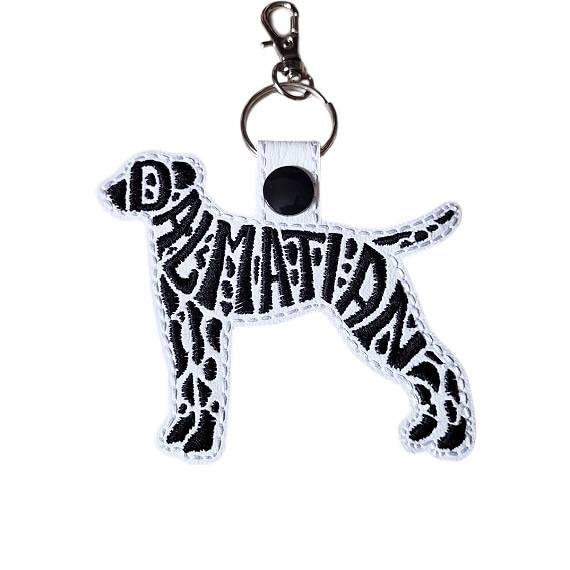 White embroidered Dalmatian word art keyring with black spotted details, black snap fastener and silver clip.