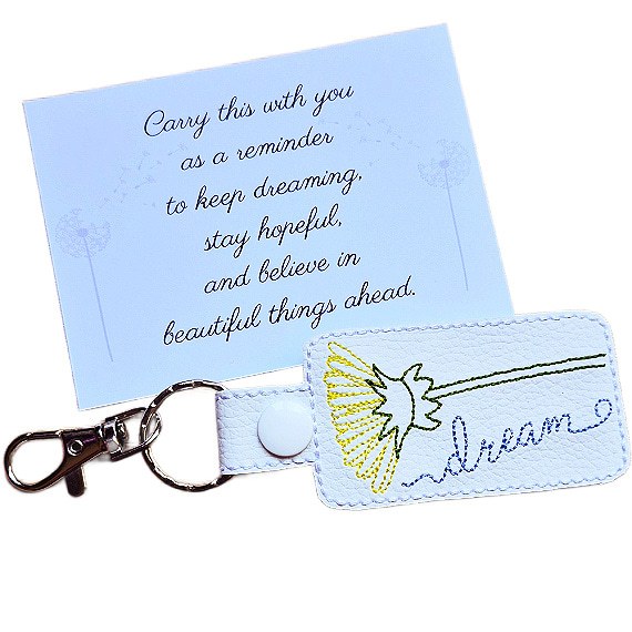 White embroidered dandelion keyring with 'dream' text, silver clip and matching keepsake card with hopeful message.