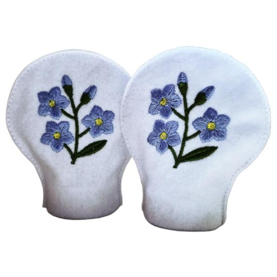 Two unlit forget me not tealight covers made from white felt, each embroidered with blue flowers, green stems and yellow flower centres.