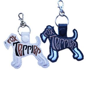 Embroidered Fox Terrier word art keyrings in black and white faux leather, shown with metal split rings and lobster clasps.