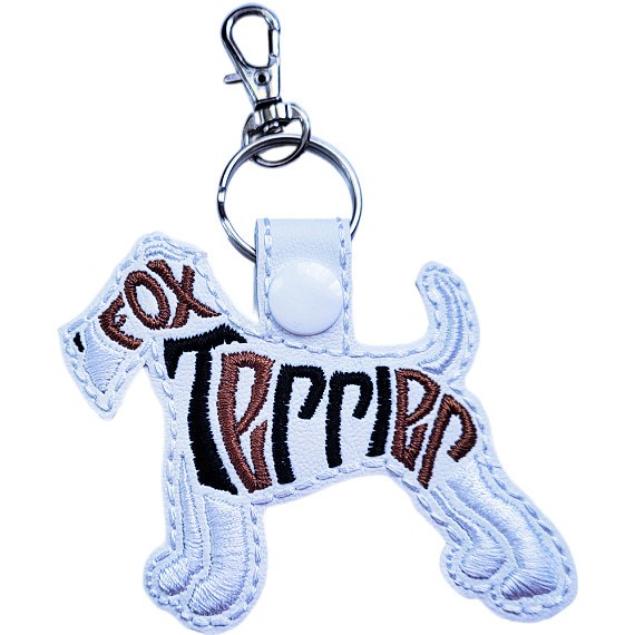 White embroidered Fox Terrier word art keyring made from faux leather, with stitched breed lettering and silver metal hardware.