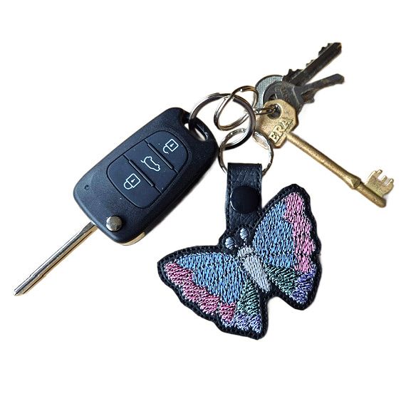 Black faux leather butterfly keyring attached to a set of keys, showing its size and everyday use.