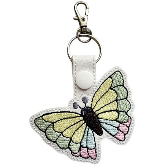 White faux leather butterfly keyring with pastel embroidered wings, black stitched body and silver metal lobster clasp.
