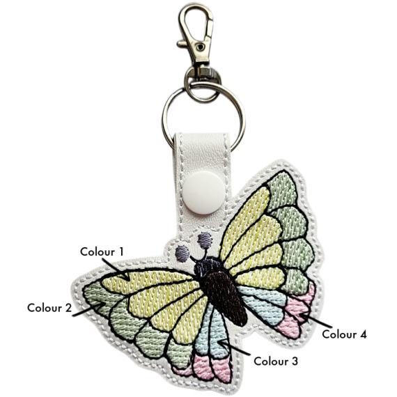 White faux leather butterfly keyring showing four labelled wing colour sections for custom embroidery choices.