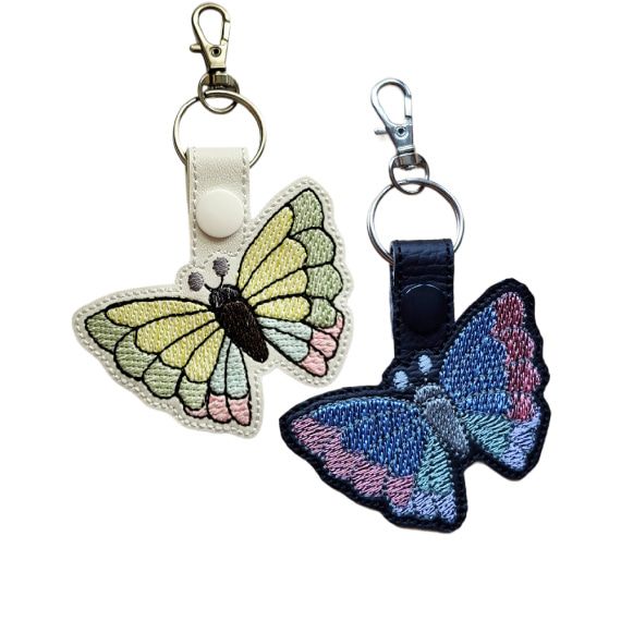 Black and white faux leather butterfly keyrings with colourful embroidered wings and metal lobster clasps.